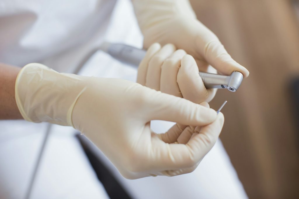 Cropped view of dental nurse wearing protective gloves preparing dental equipment